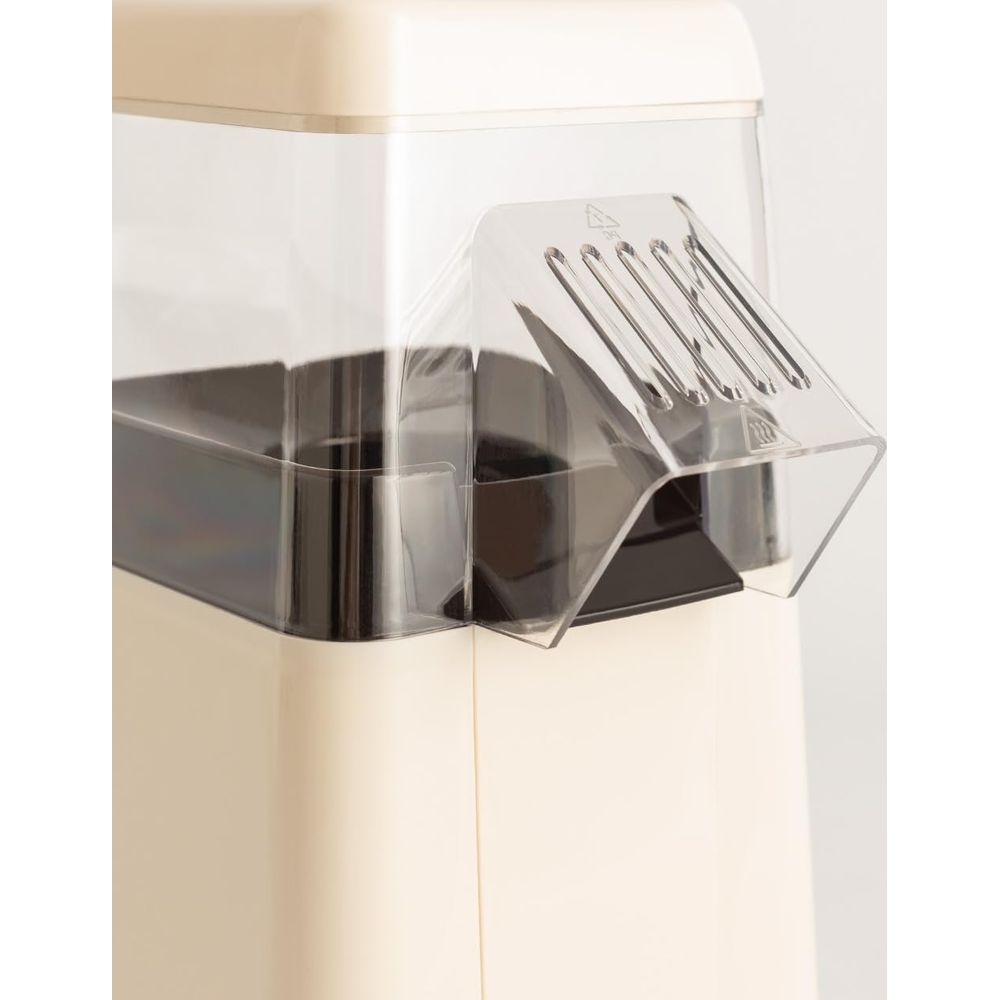 Máquina de palomitas de color crema con tapa transparente y canaleta dispensadora.