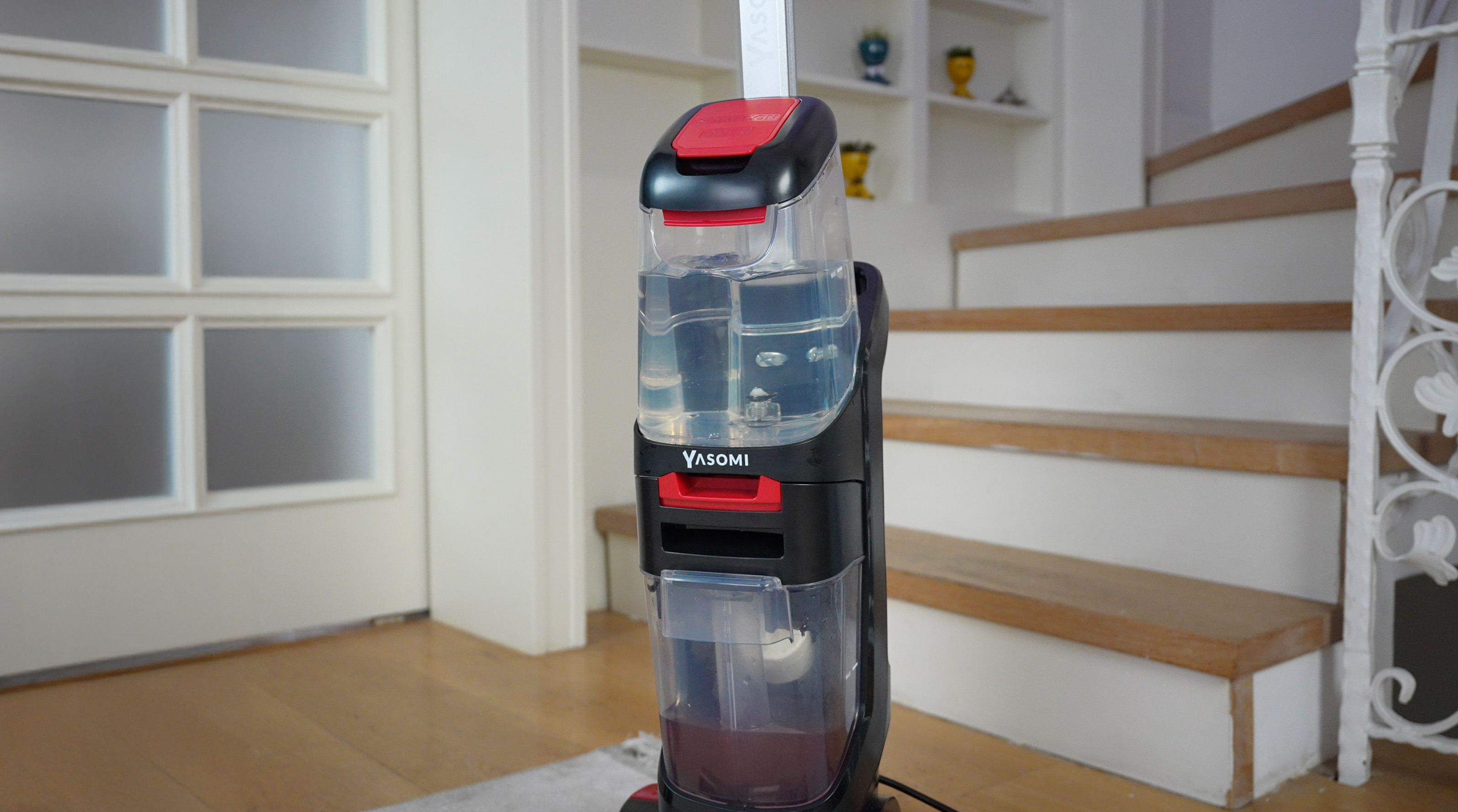Siyah ve kırmızı ıslak/kuru elektrikli süpürge ahşap zeminde duruyor.