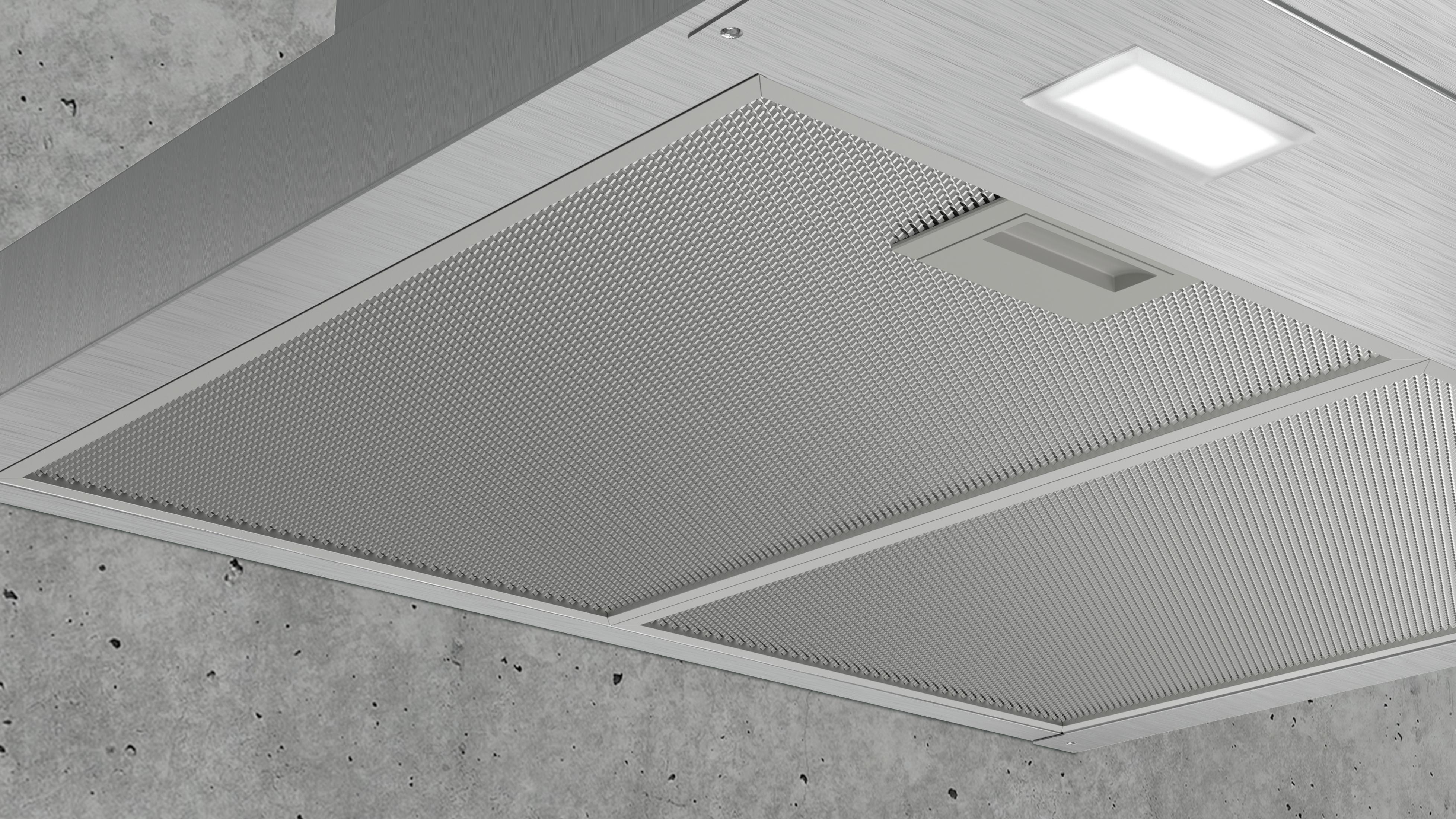 Cappa in acciaio inox spazzolato con filtro a rete e luce LED su cemento.