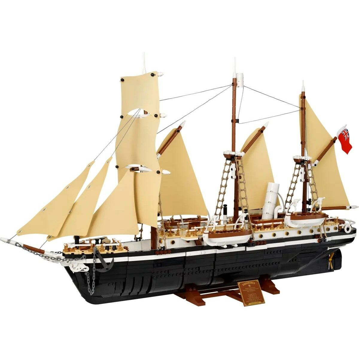 Ein detailliertes Modellschiff mit schwarzen Rumpf, weißen Aufbauten und beigen Segeln.