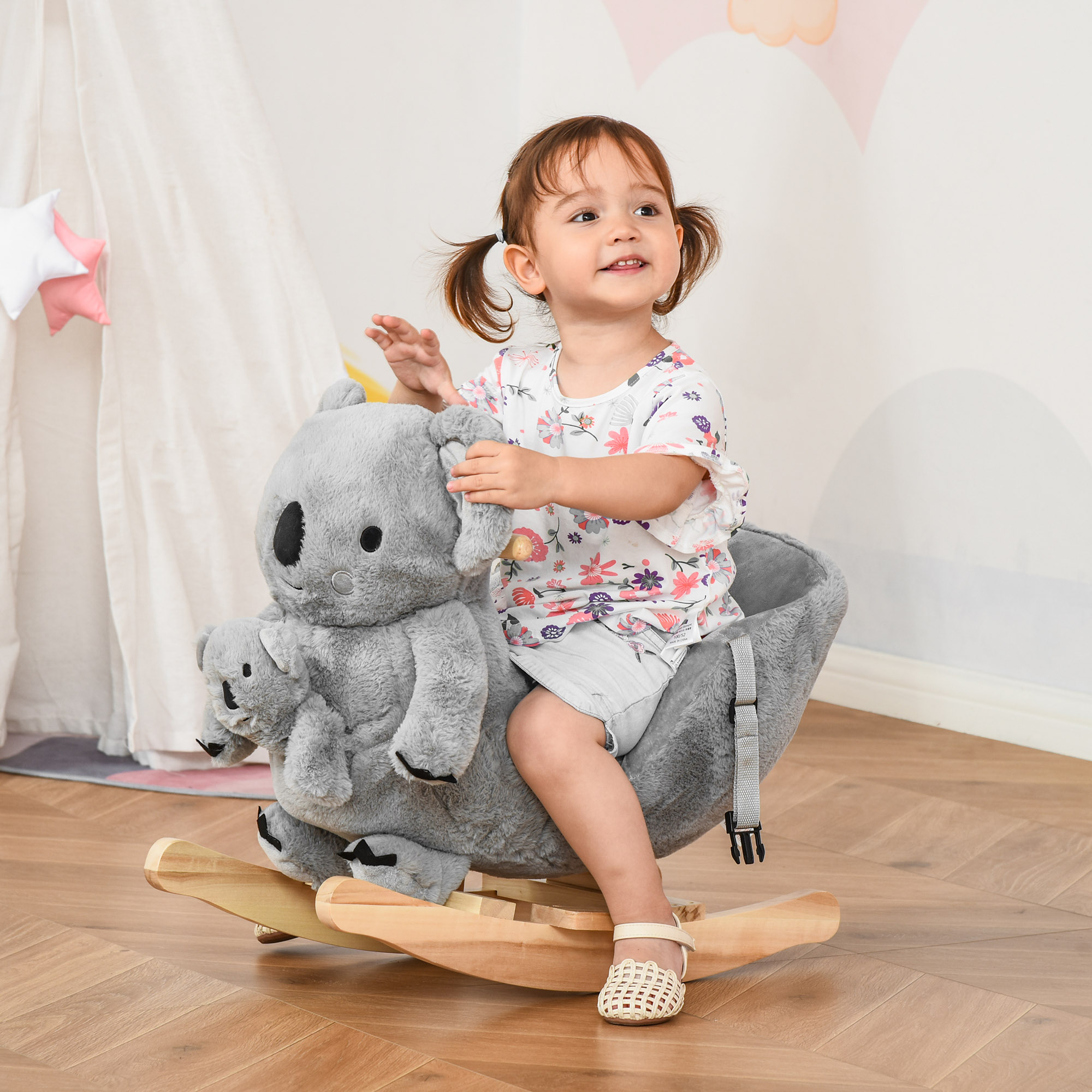 Una niña se sienta en un balancín de koala gris con un koala bebé.