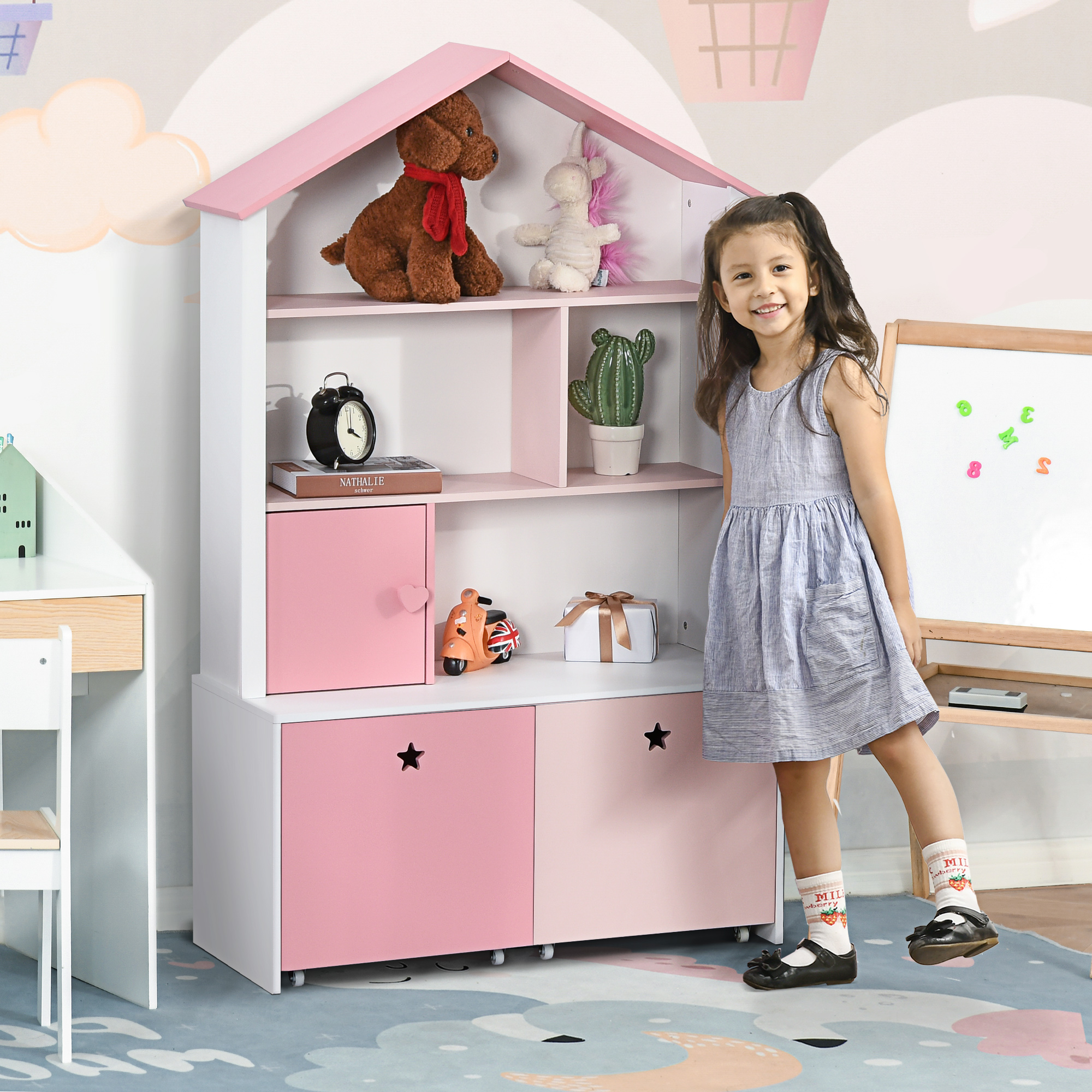 Una niña está junto a una estantería rosa en forma de casa con juguetes y libros.