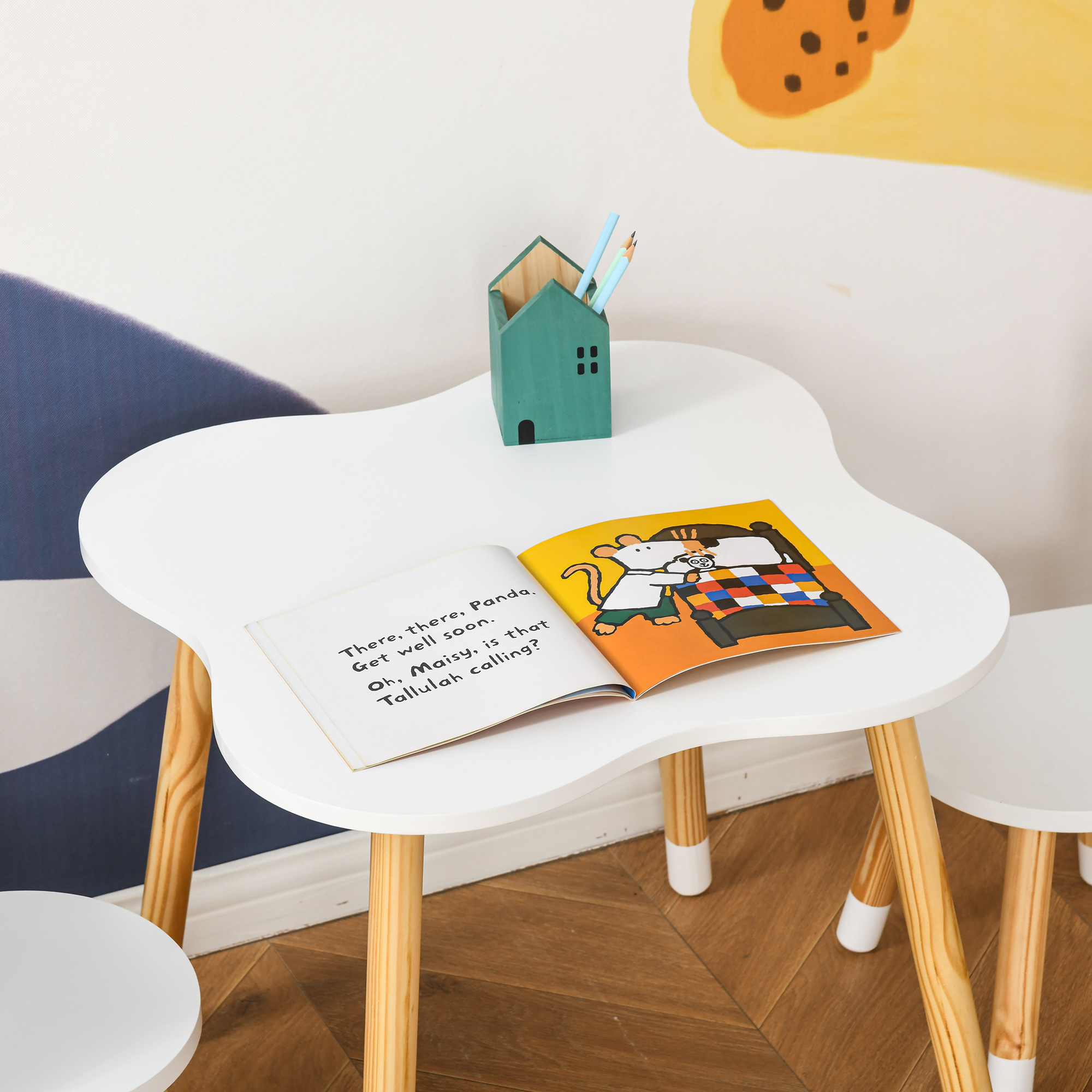 Un libro infantil abierto sobre una mesa blanca. Un portalápices verde cerca.