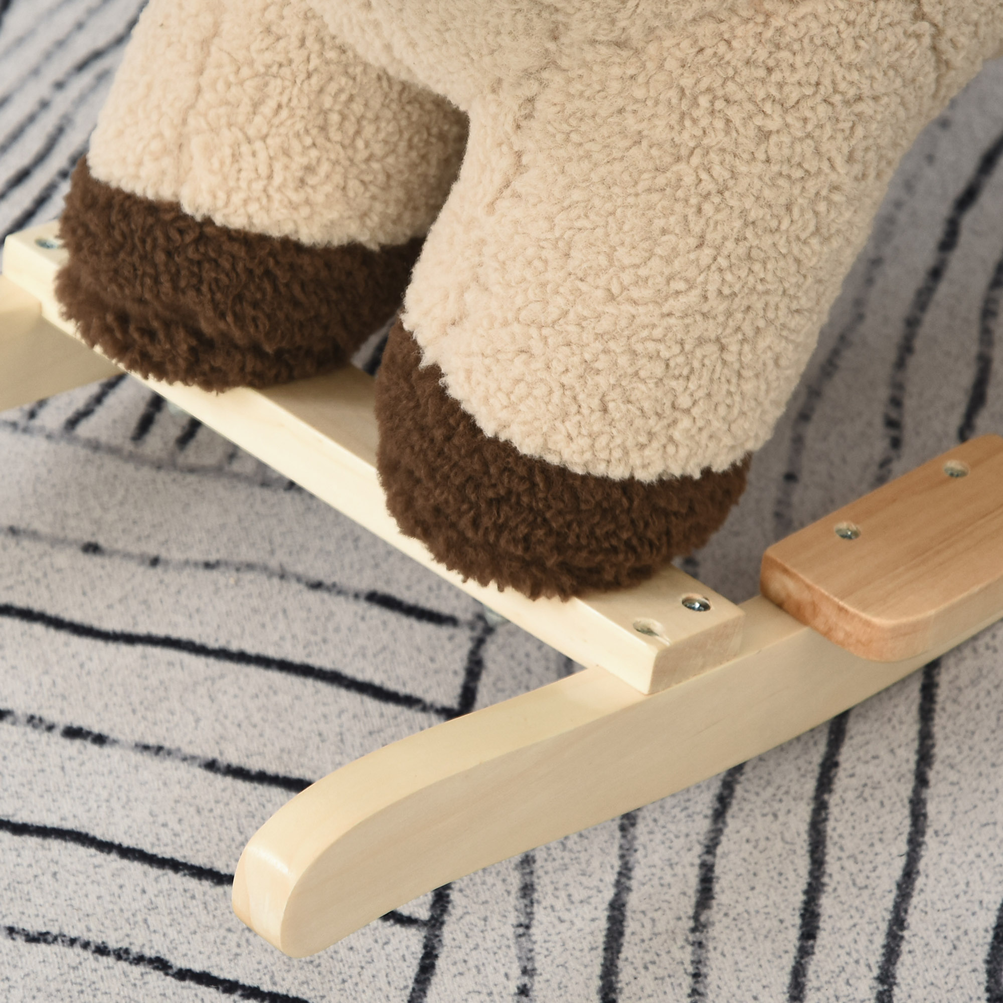 Un peluche beige y marrón se asienta sobre una base de madera para mecer sobre una alfombra.