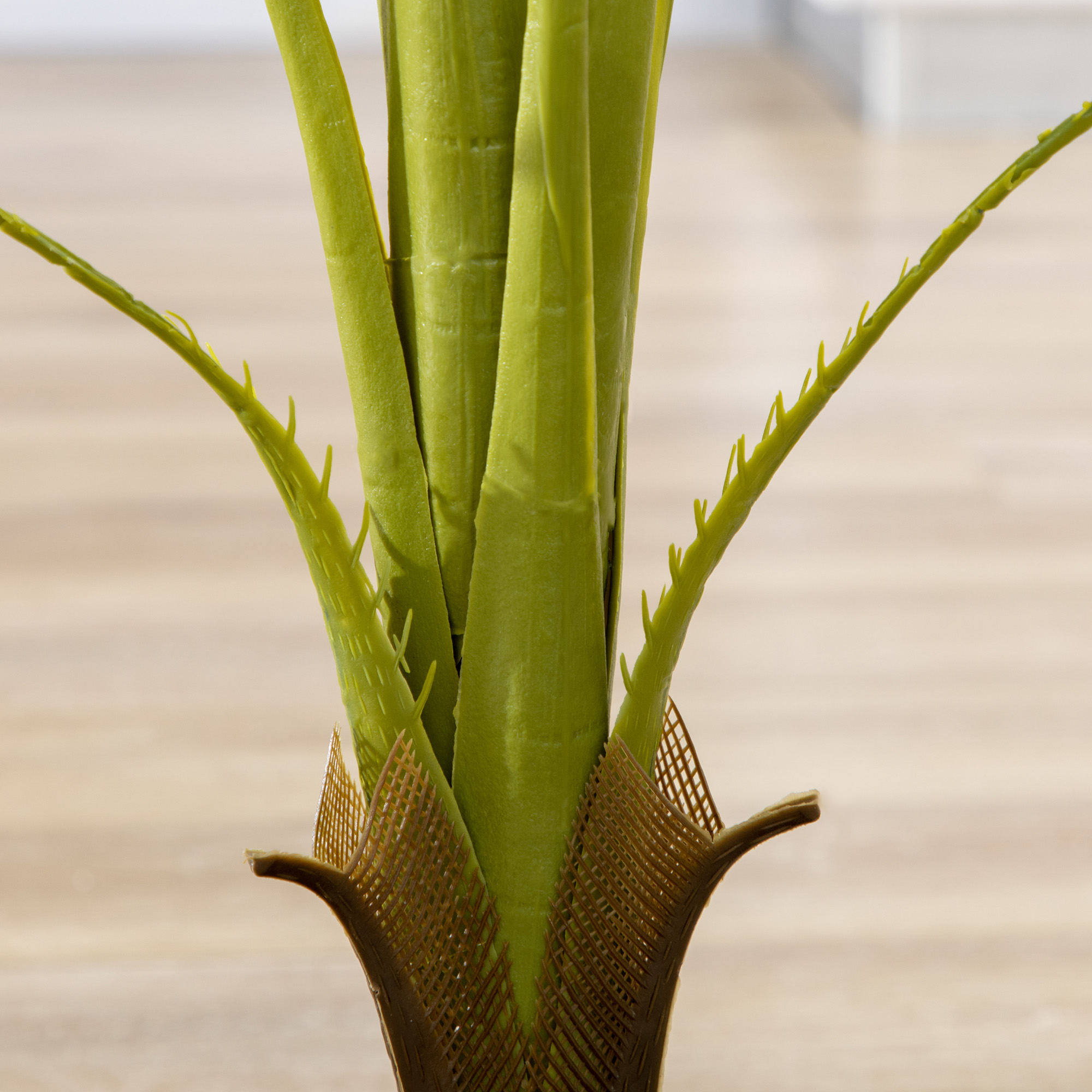 Follaje verde con detalles de red marrón sobre suelo de madera claro.