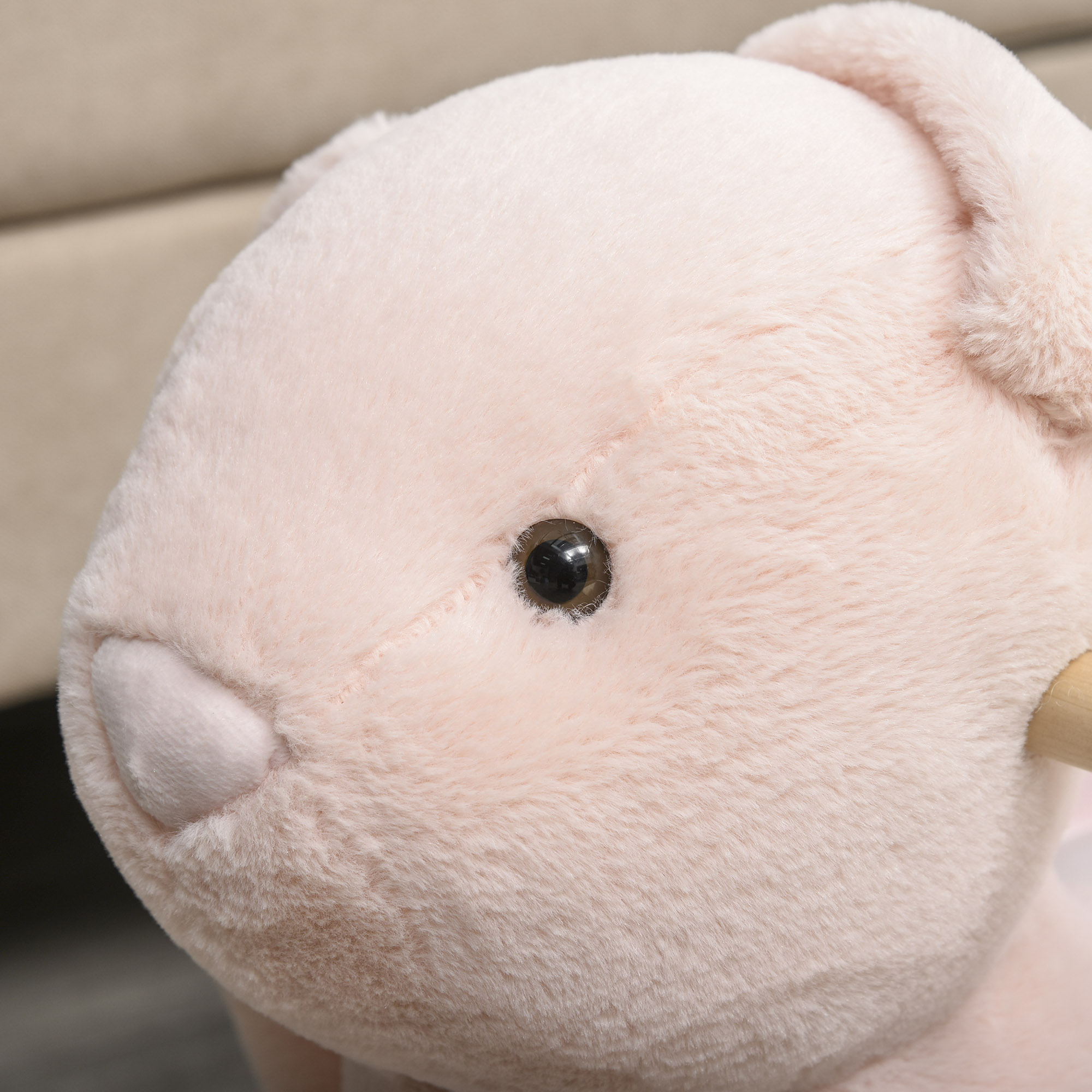 Primer plano de un conejito de peluche rosa con ojo negro y partes de madera.