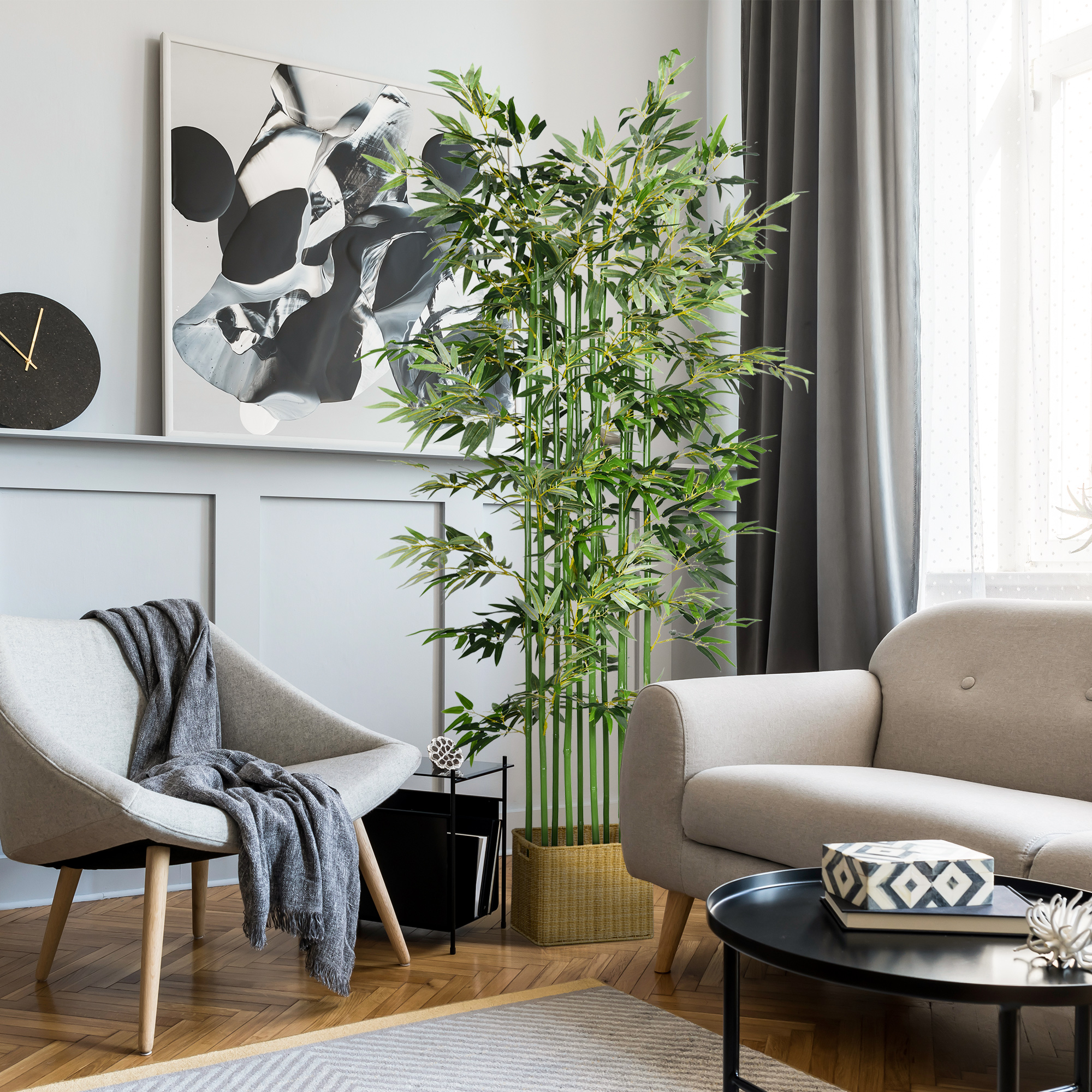 Un sillón gris claro con manta junto a un sofá. Un árbol de bambú cerca.