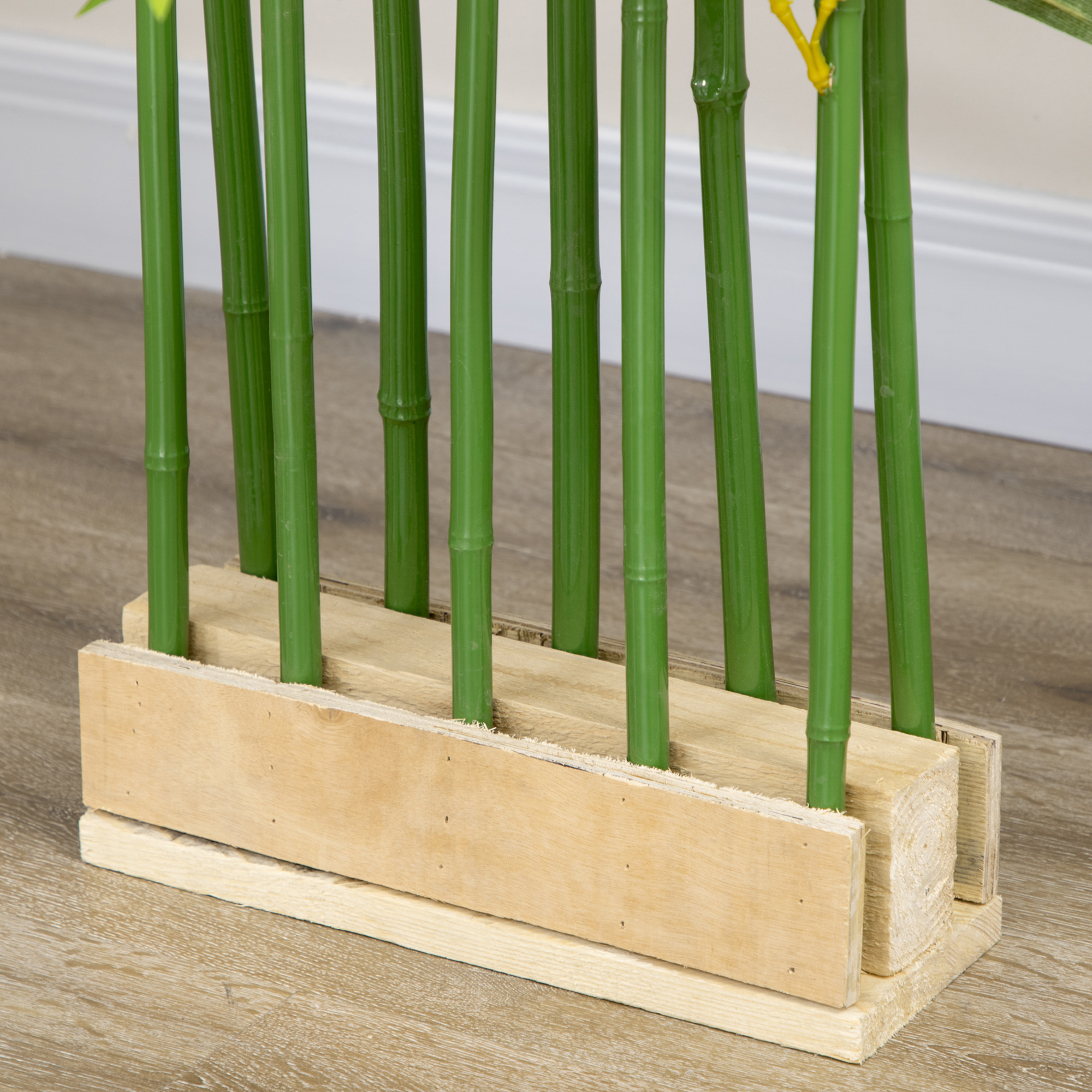 Cañas de bambú verdes en un bloque de madera sobre suelo de madera.