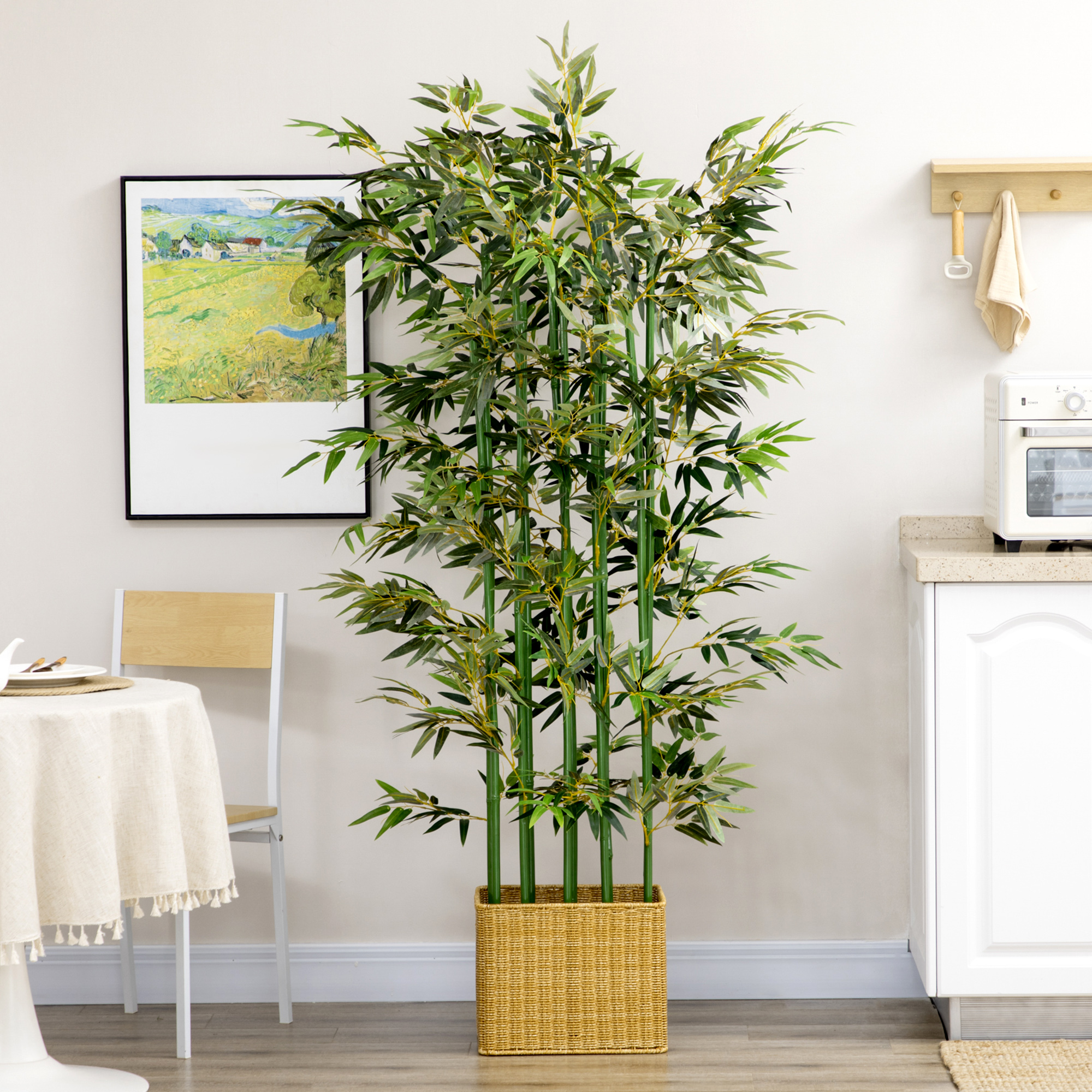 Una gran planta artificial de bambú en una cesta tejida está junto a una mesa.