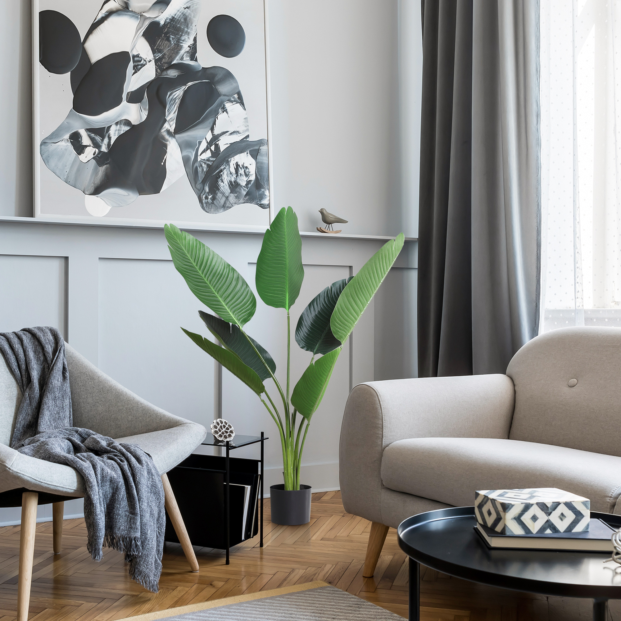 Una sala de estar gris claro con sillón, sofá, plantas y obra de arte.