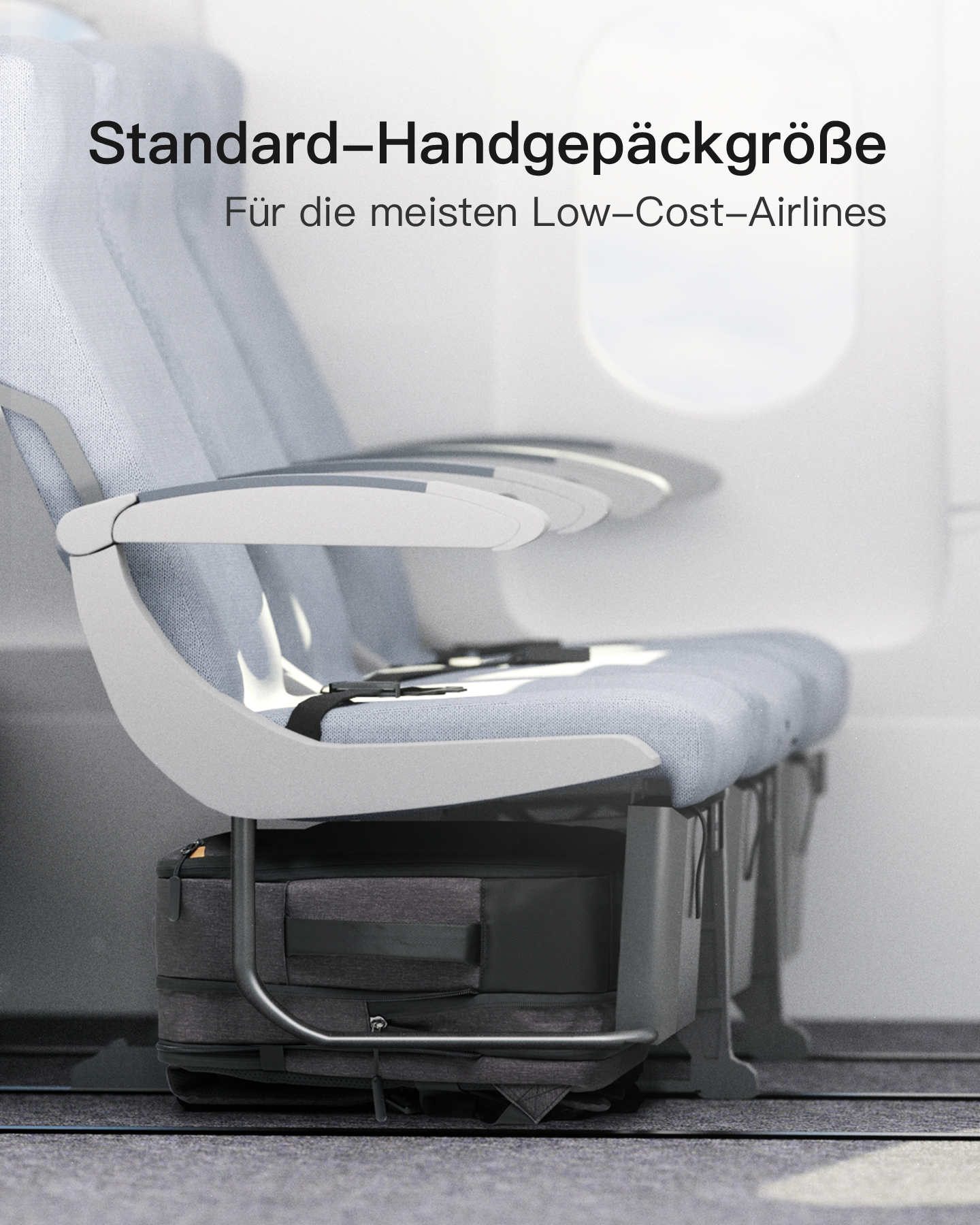 Grauer Koffer unter Flugzeugsitzen mit Text über Handgepäckgröße.