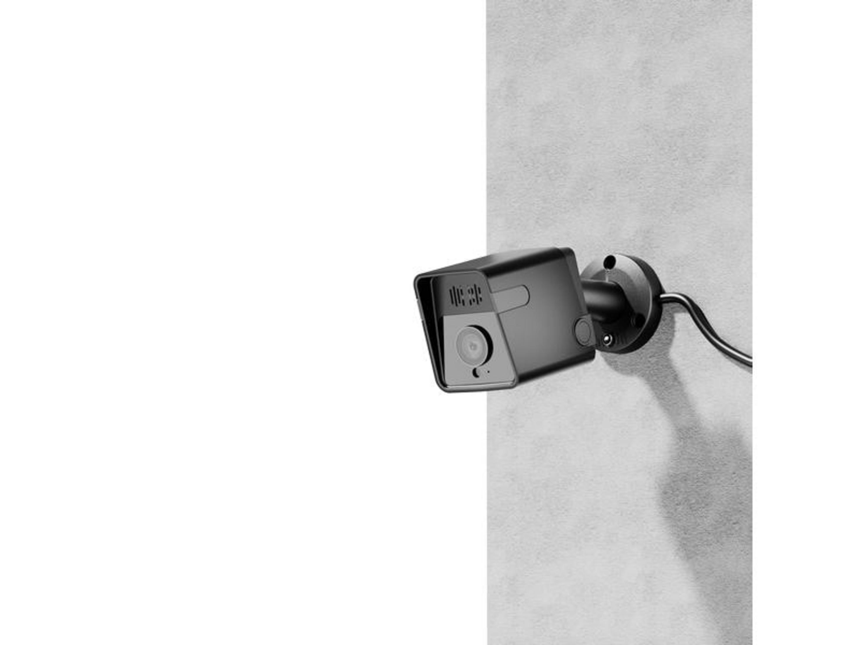 Una telecamera di sicurezza nera è montata su un muro, con cavo.