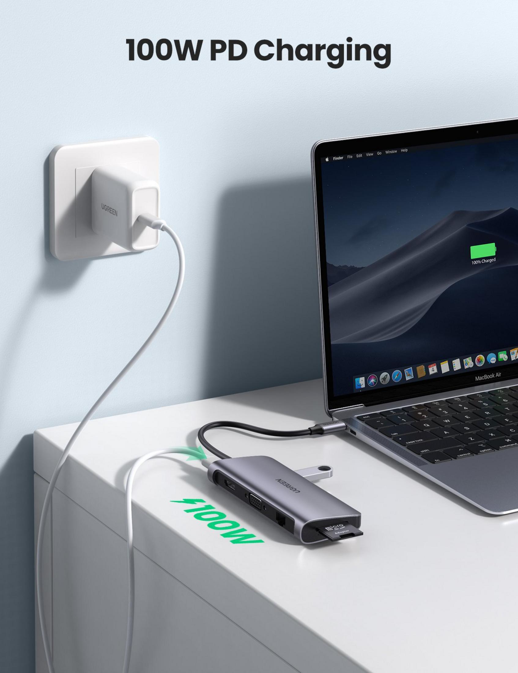 A laptop hub charges a MacBook Air via a wall-plugged power adapter.