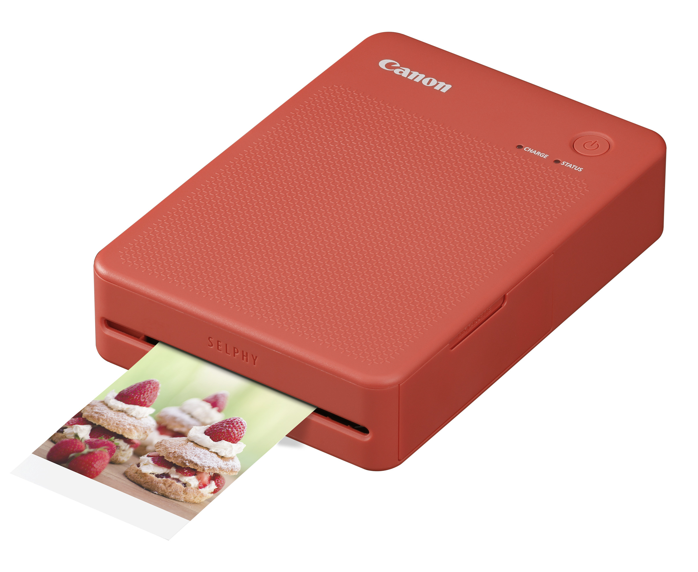 Una impresora Canon SELPHY roja imprime una imagen de pasteles de fresa con nata.