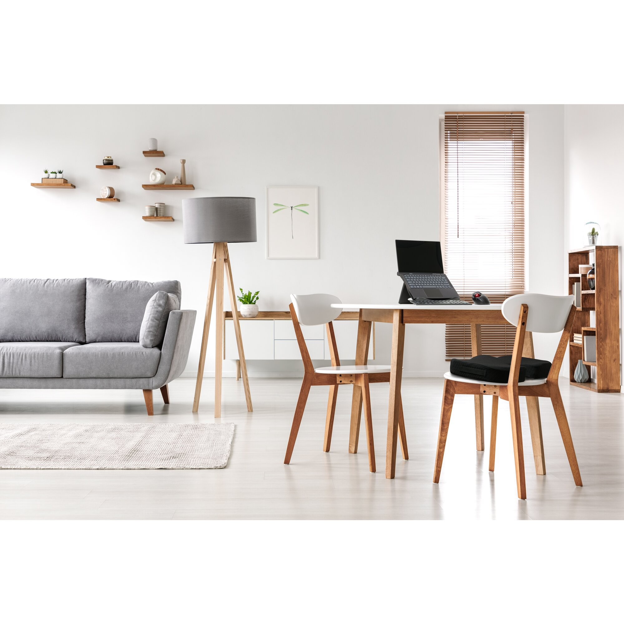 Modern living room with grey sofa, wooden table, chairs, lamp and bookshelf.