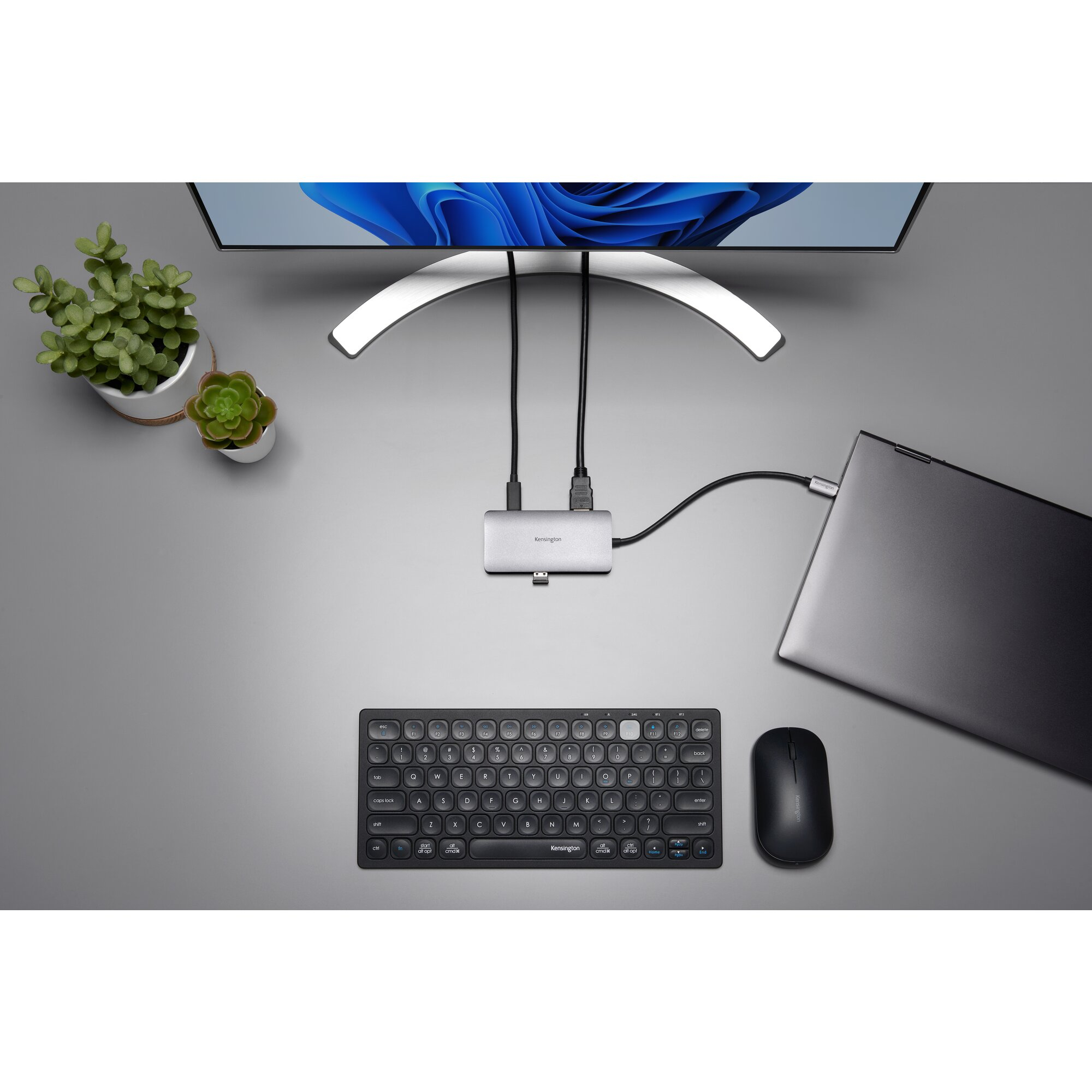 Una postazione da scrivania con monitor, laptop, docking station, tastiera e mouse.