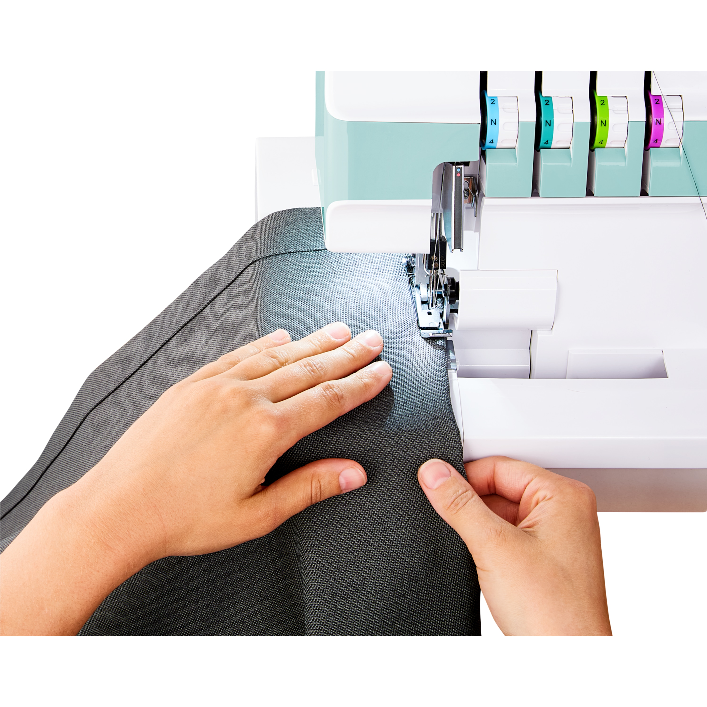 Dłonie prowadzą ciemny materiał pod maszynę do szycia.