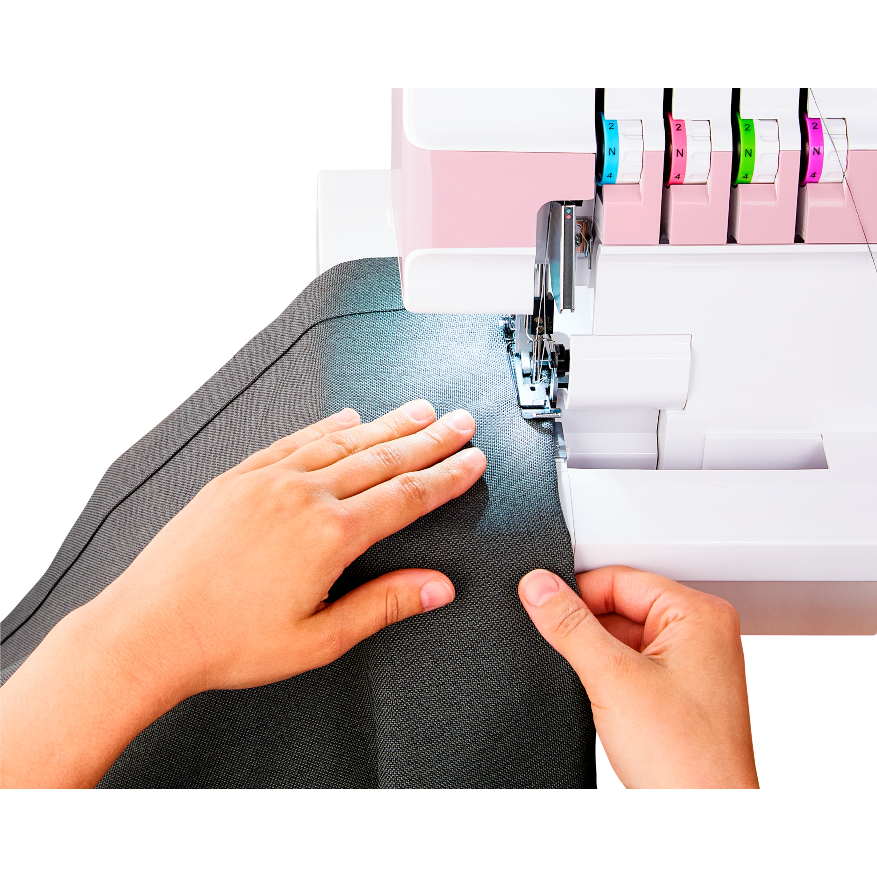Dłonie prowadzą ciemny materiał pod maszynę do szycia z różowymi akcentami.