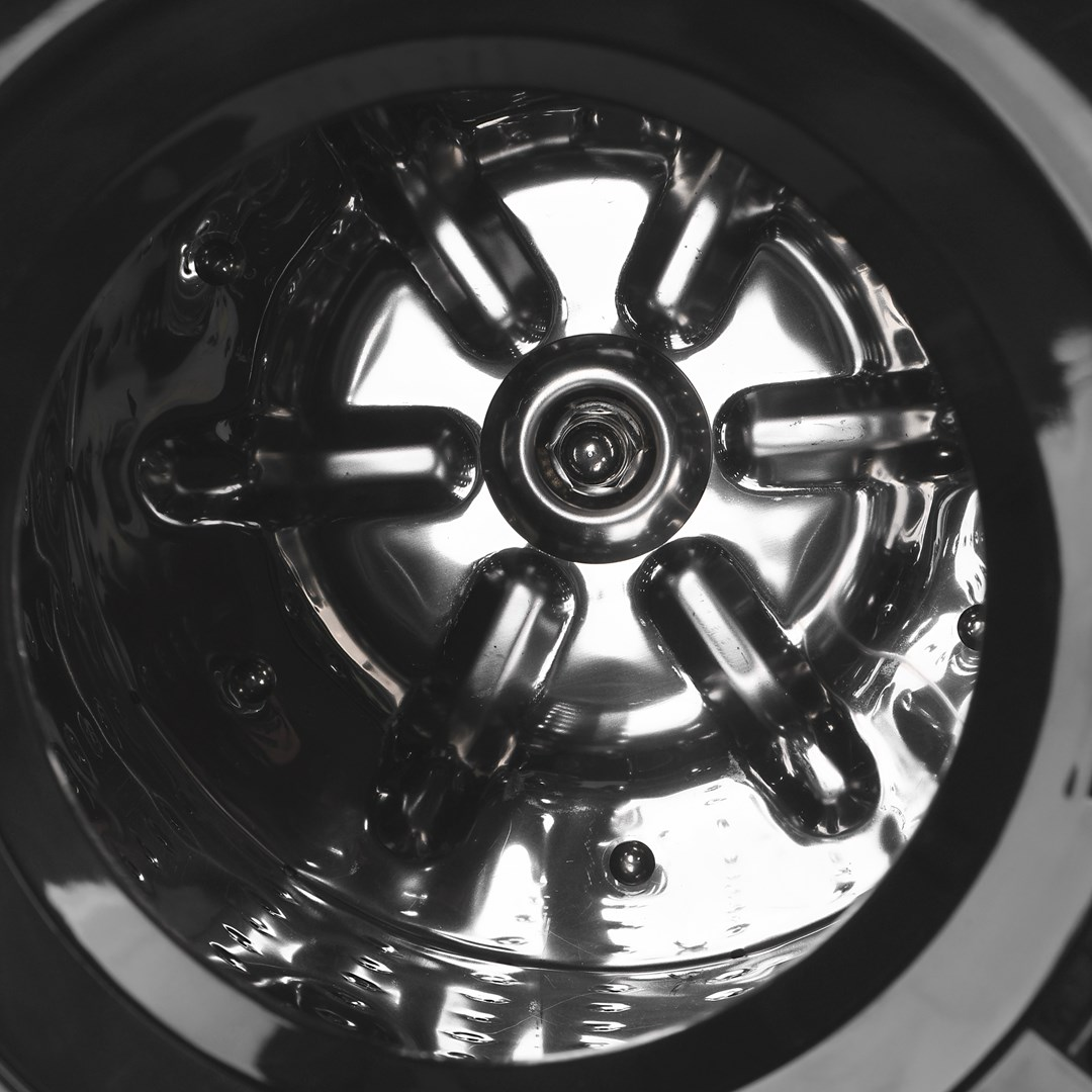 Błyszczące metalowe wnętrze bębna z sześcioma żebrami promieniującymi z centralnej piasty.