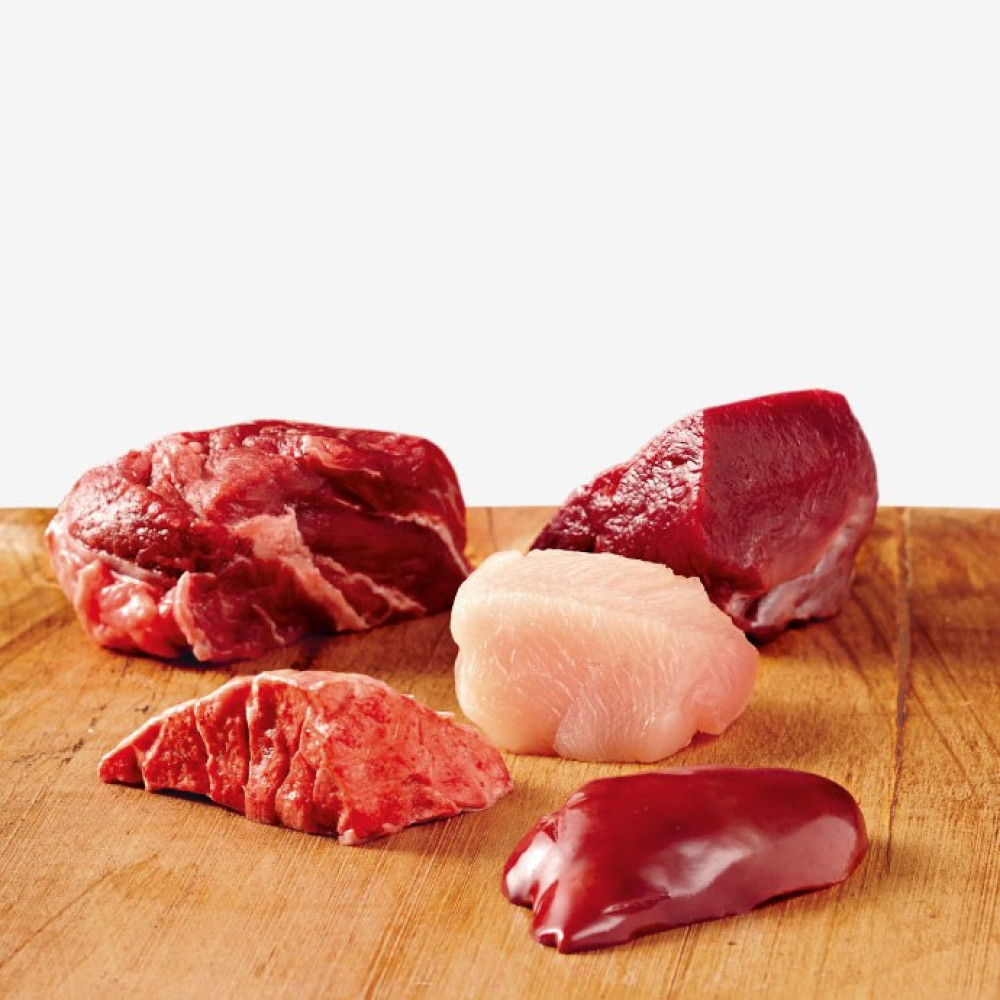 Cztery kawałki surowego mięsa ułożone na drewnianej powierzchni.