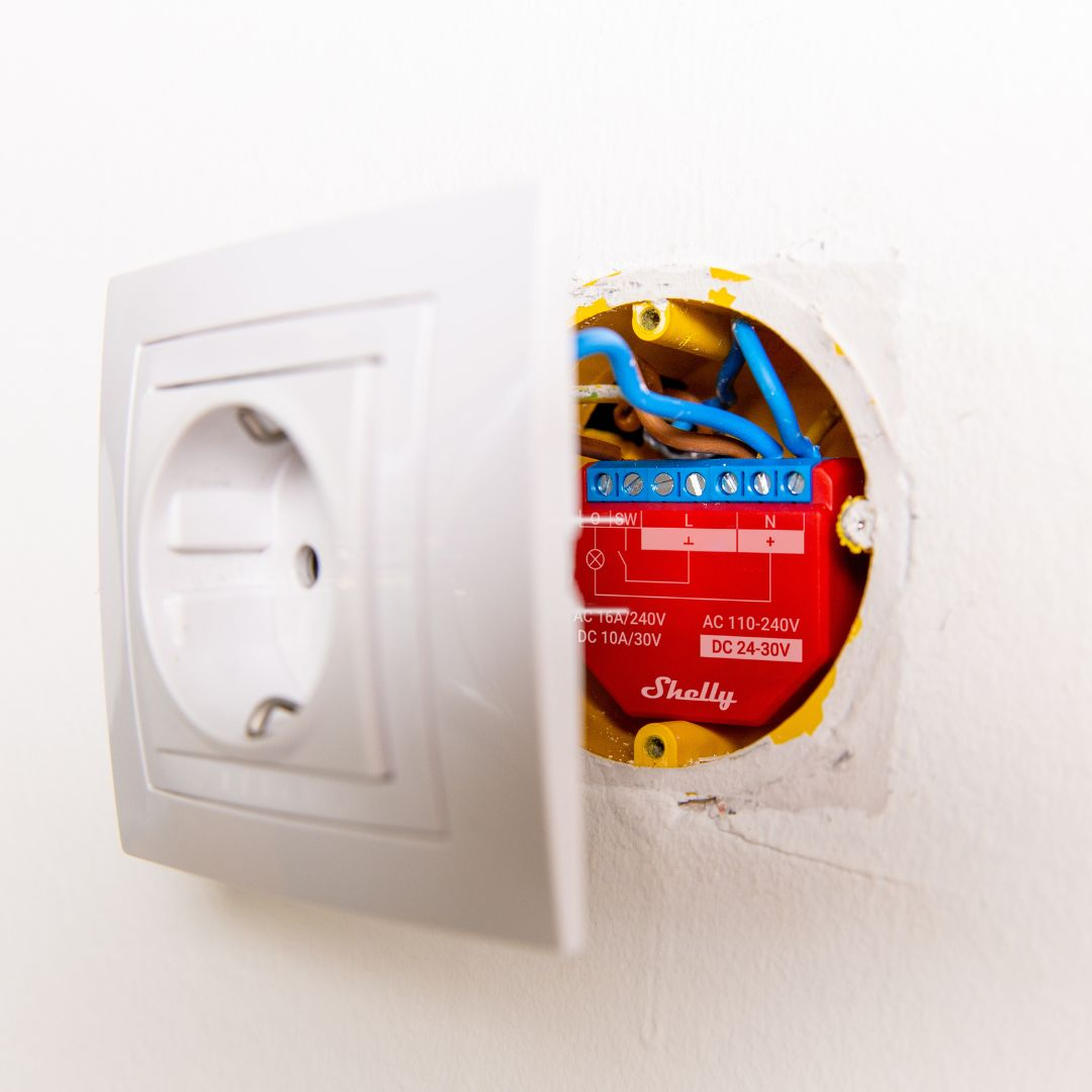 Presa elettrica bianca con modulo smart home Shelly rosso aperto.