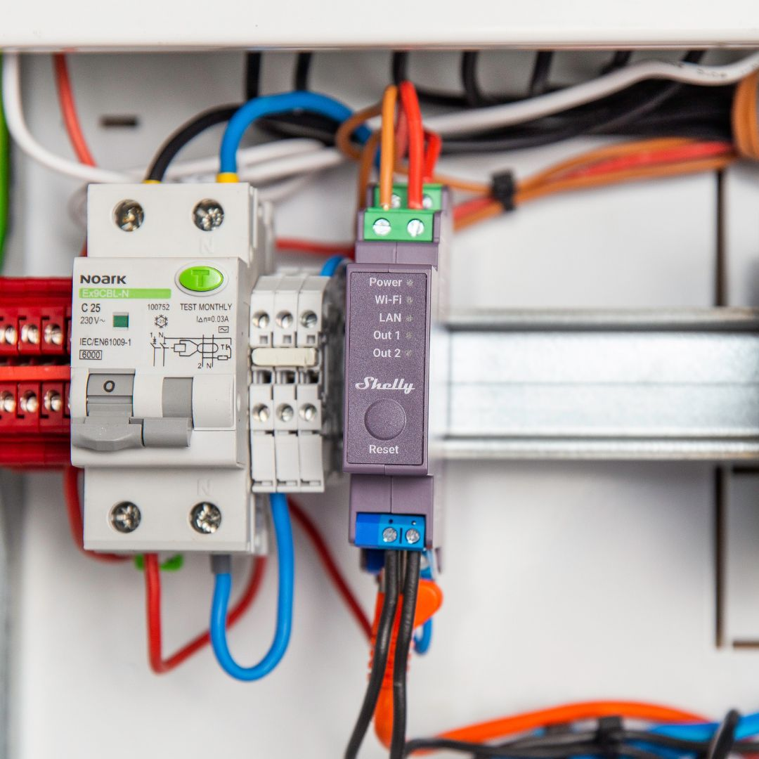 Wyłącznik nadprądowy i urządzenie Shelly z przewodami w panelu elektrycznym.
