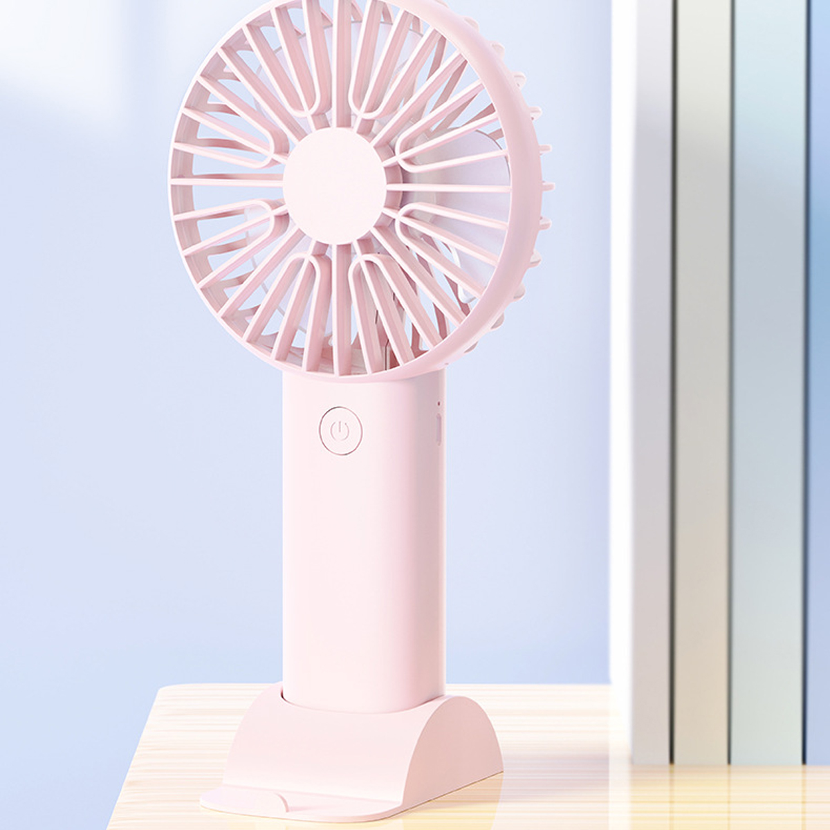 Ein kleiner, rosafarbener Handventilator mit einem runden Kopf und einem Griff.