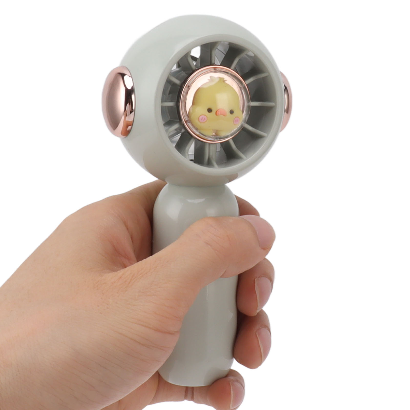 Eine Hand hält einen kleinen, grauen Ventilator mit einem gelben Küken-Design.