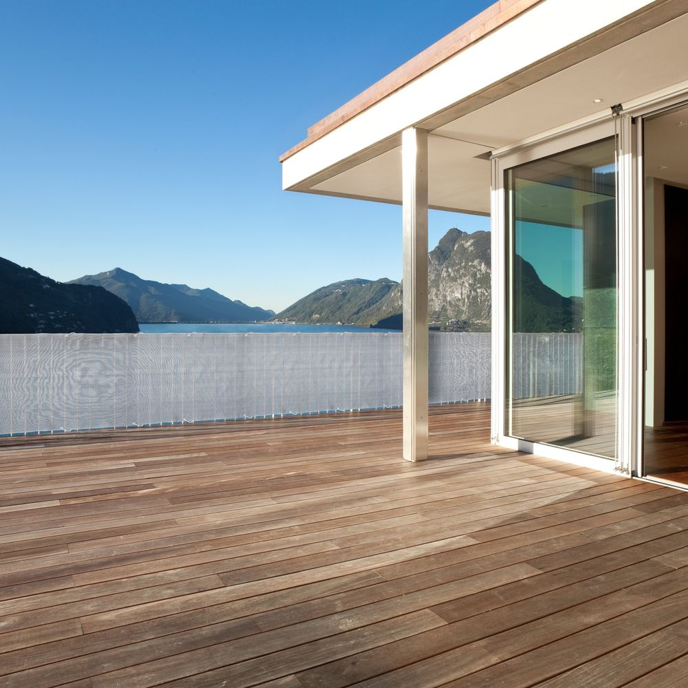 Holzdeck mit Blick auf einen See und Berge, mit Glasfront.