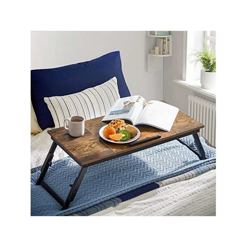 Un tavolino da vassoio in legno con colazione su un letto con cuscini blu.