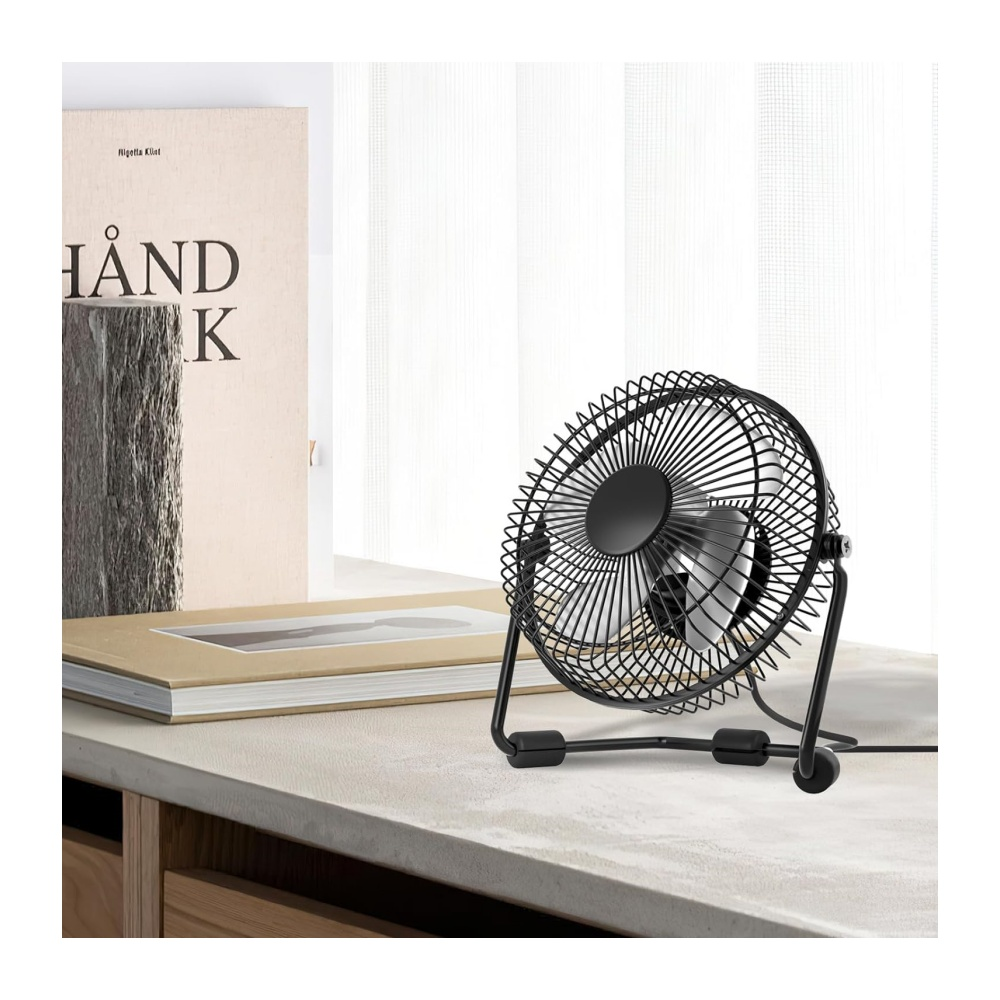 Kleiner schwarzer Ventilator auf einem Tisch neben Büchern.
