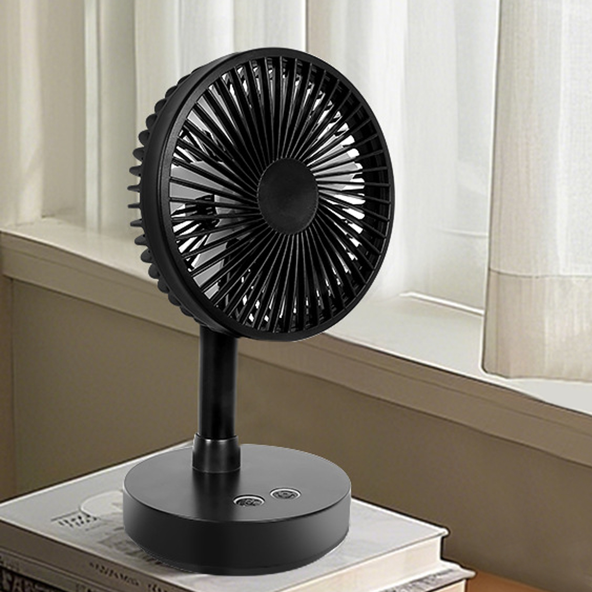 Ein schwarzer Tischventilator steht auf Büchern vor einem Fenster mit weißen Vorhängen.
