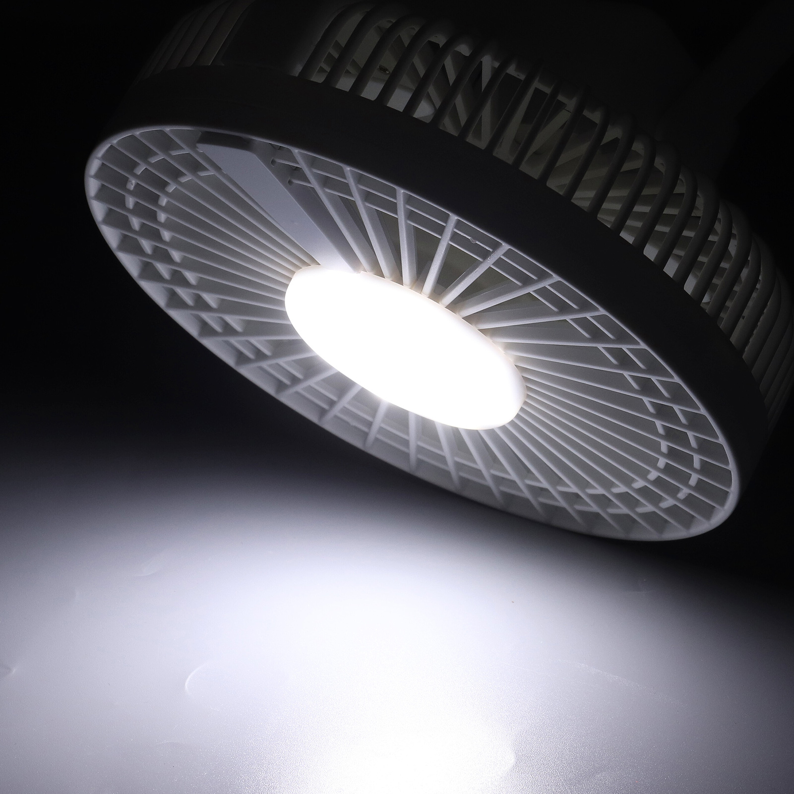 Ein weißer Ventilator mit beleuchtetem Mittelteil auf dunklem Hintergrund.