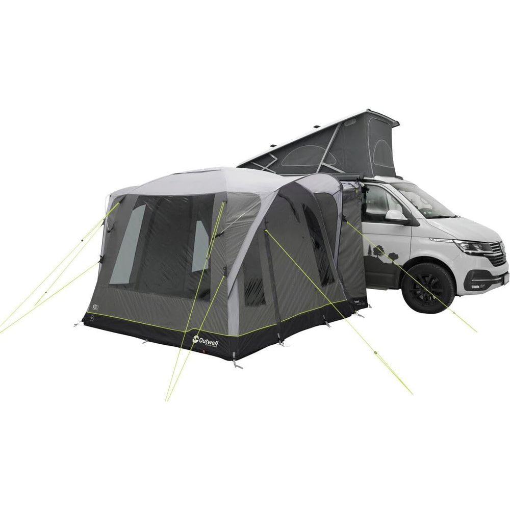 Una tenda grigia è attaccata a un camper bianco con tetto a soffietto.
