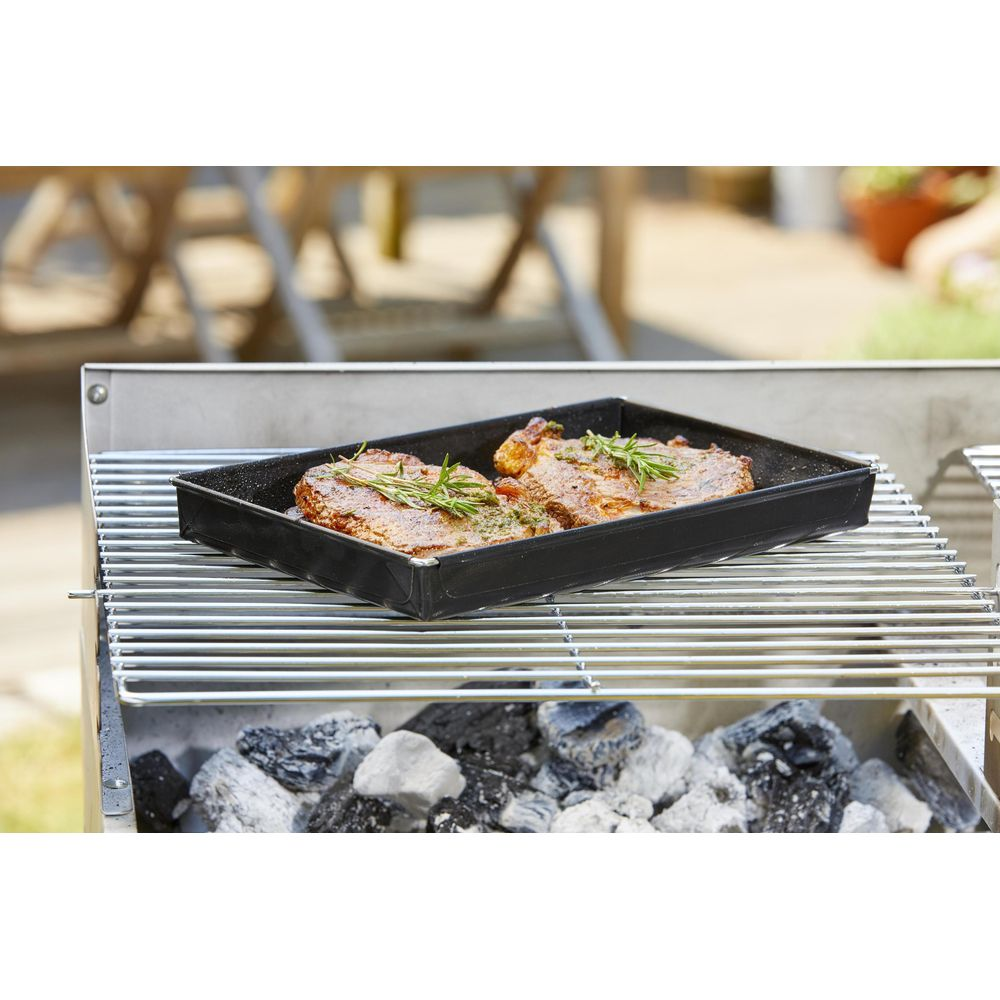 Zwei Steaks in einer schwarzen Grillschale mit Rosmarin auf einem Grill.