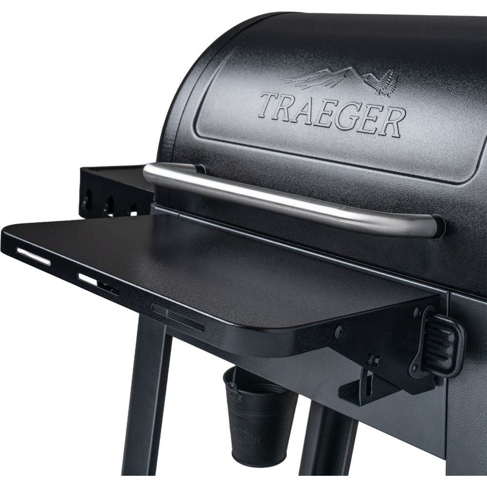 Nahaufnahme eines schwarzen Traeger-Grills mit silbernem Griff und schwarzem Seitenregal.