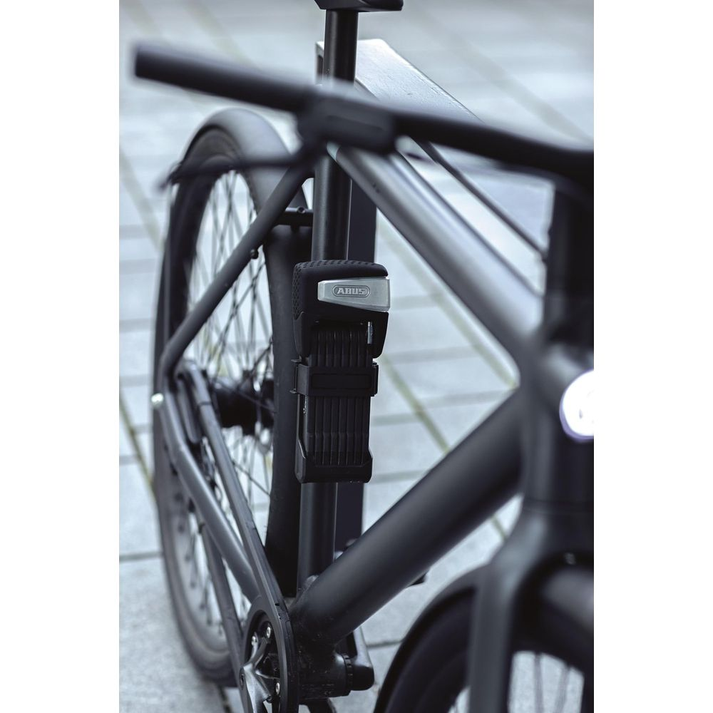 Ein schwarzes Fahrrad mit einem Faltschloss, das am Rahmen befestigt ist.