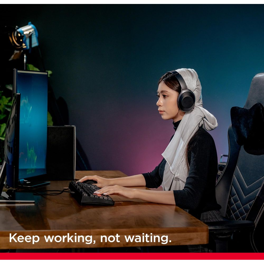 Eine Frau mit Kopfhörern und Hijab tippt auf einer Tastatur vor einem Computer.