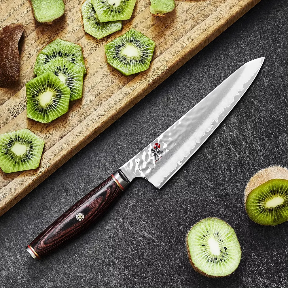 Un couteau à côté de kiwis coupés sur une planche à découper en bois.