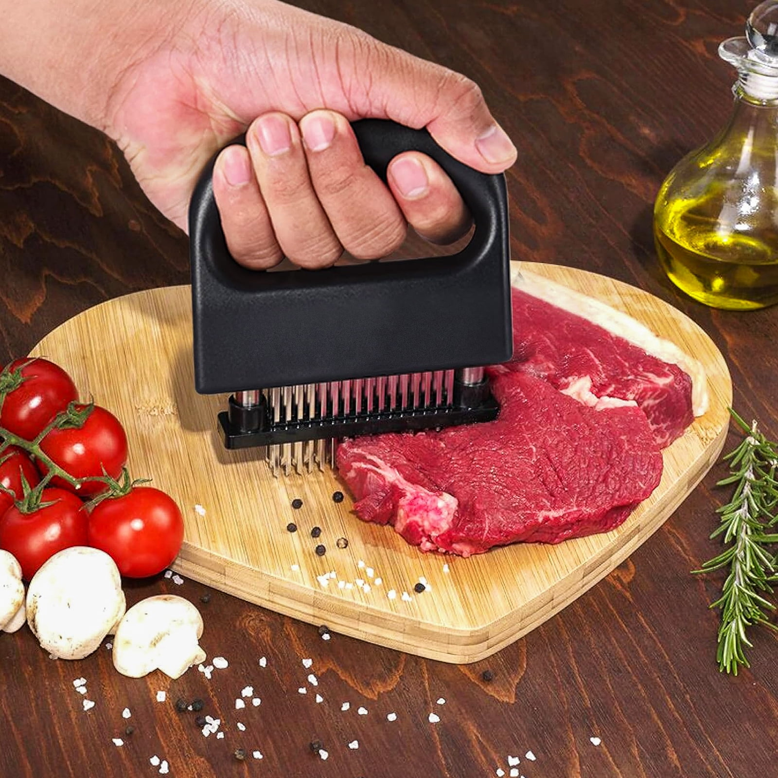 Hand benutzt Fleischklopfer auf rohes Rindfleisch auf Holzbrett mit Tomaten.