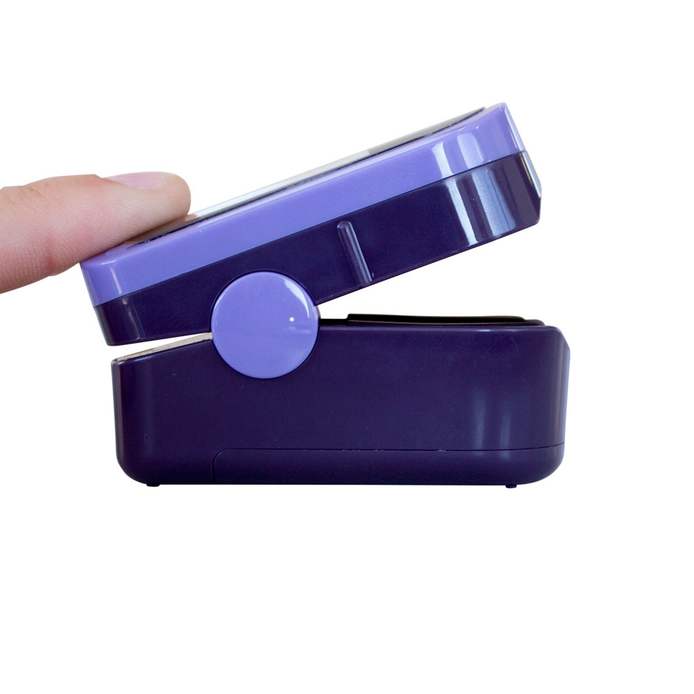 Un dedo presiona un oxímetro púrpura y violeta. Fondo blanco.