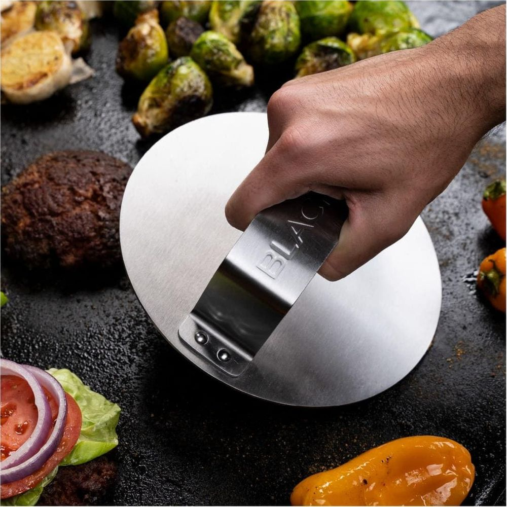 Main presse un burger avec une presse sur de la viande, avec des burgers, choux et poivrons.