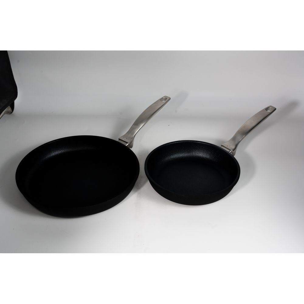 Deux poêles noires à manches argentés sur fond blanc.