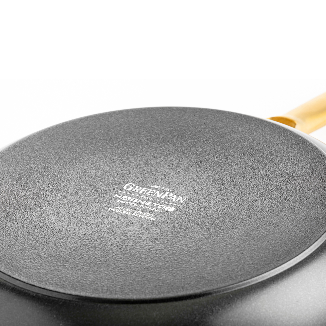 Nahaufnahme der Unterseite einer Bratpfanne mit dem Logo 'Greenpan' und 'Magneto'.