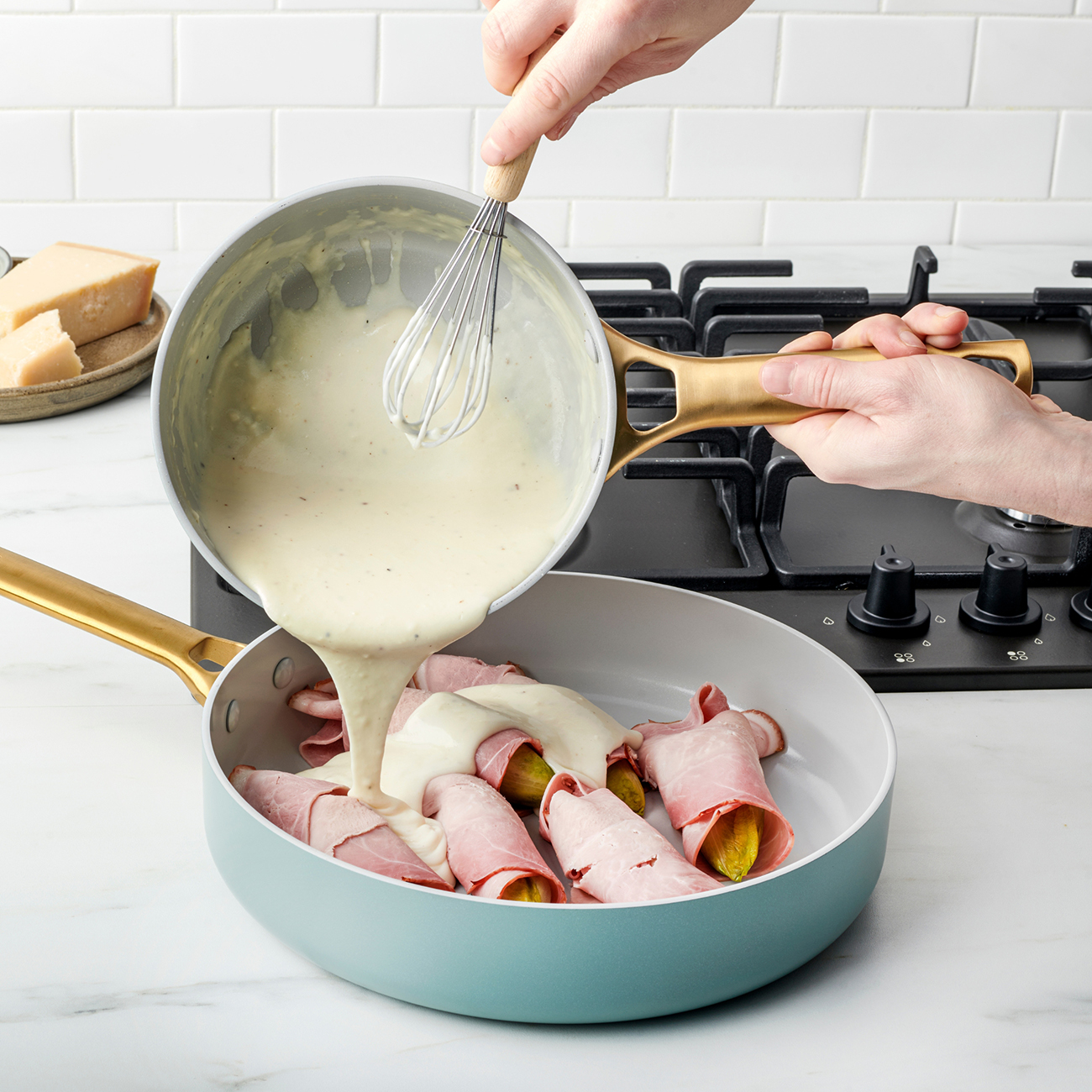Sahnesoße wird aus einem Topf in eine Pfanne mit Schinkenröllchen mit Gurken gegossen.
