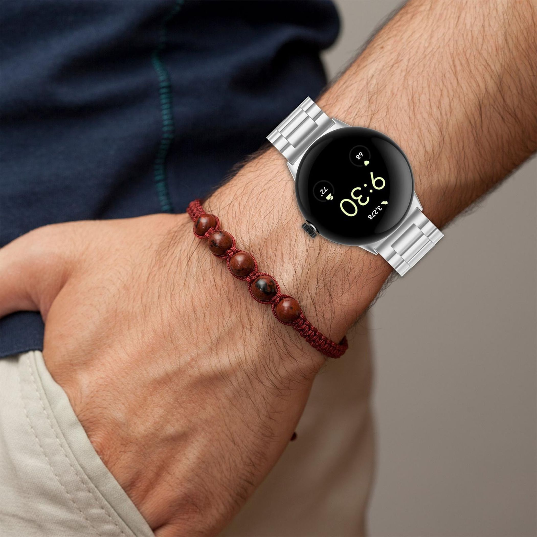 Eine Uhr am Arm mit roten Perlen und einer blauen