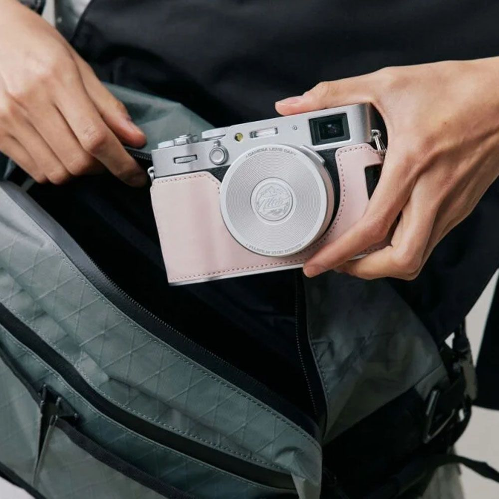 Un appareil photo dans un étui rose est placé dans un sac gris.