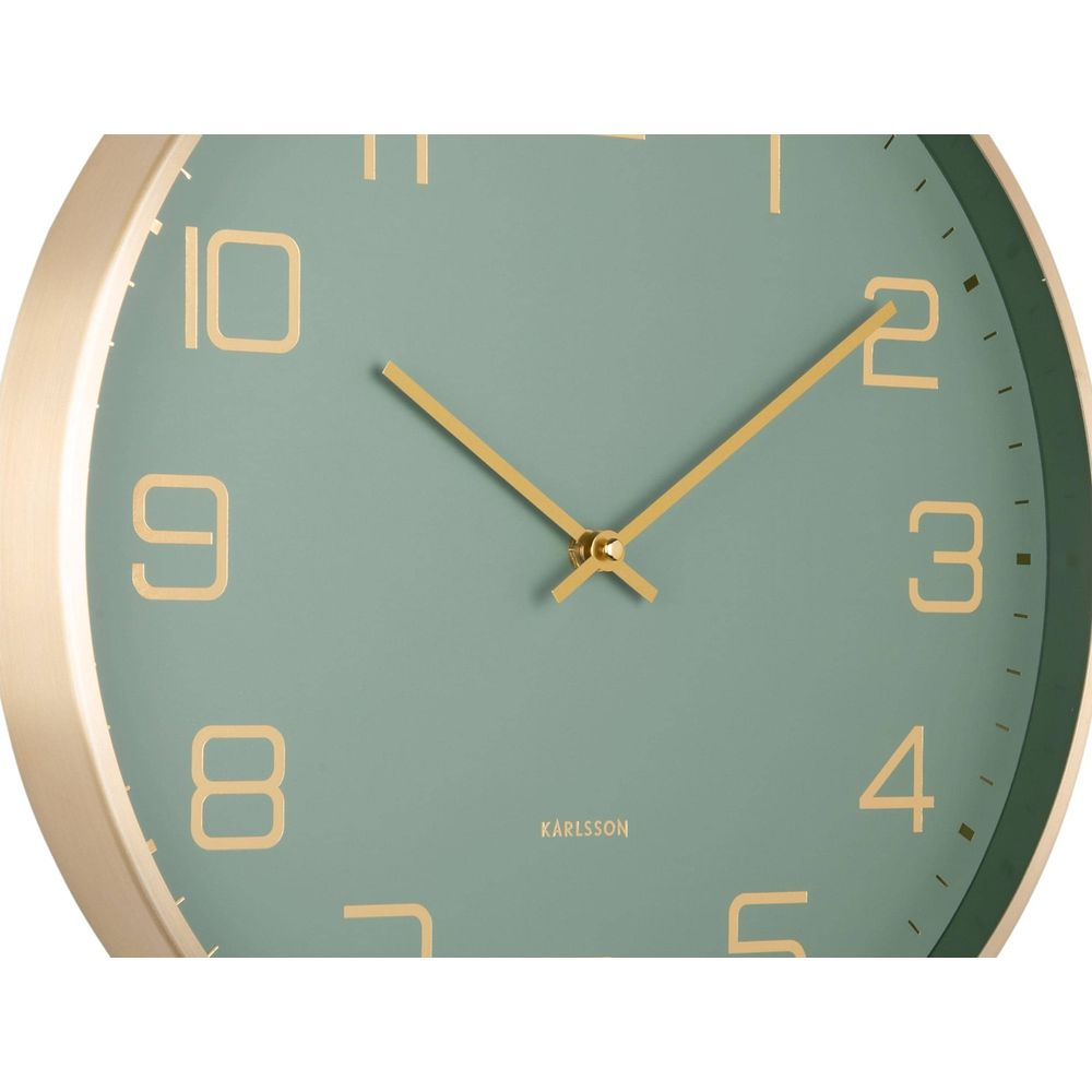 Eine Nahaufnahme einer Karlsson-Wanduhr mit grünem Zifferblatt und goldenen Zahlen und Zeigern.
