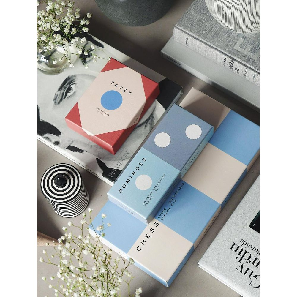 Une collection de jeux de société dont Yatzy, Domino et Échecs, sur un livre.