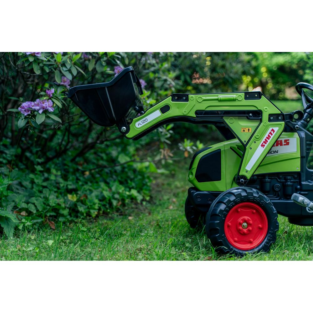 Grüner Spielzeugtraktor mit Lader vorne, auf Gras mit lila Blumen.